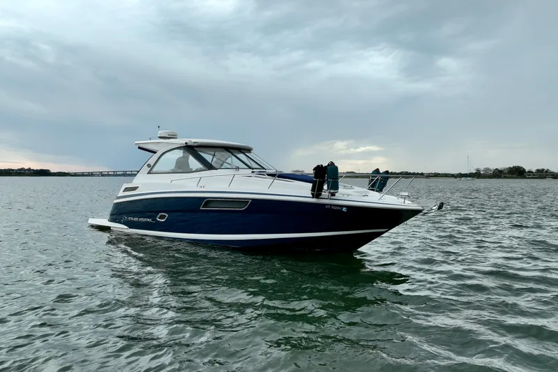 Slide: The Image of 2017 Regal 35 Sport Coupe boat on calm water under cloudy sky. - 13