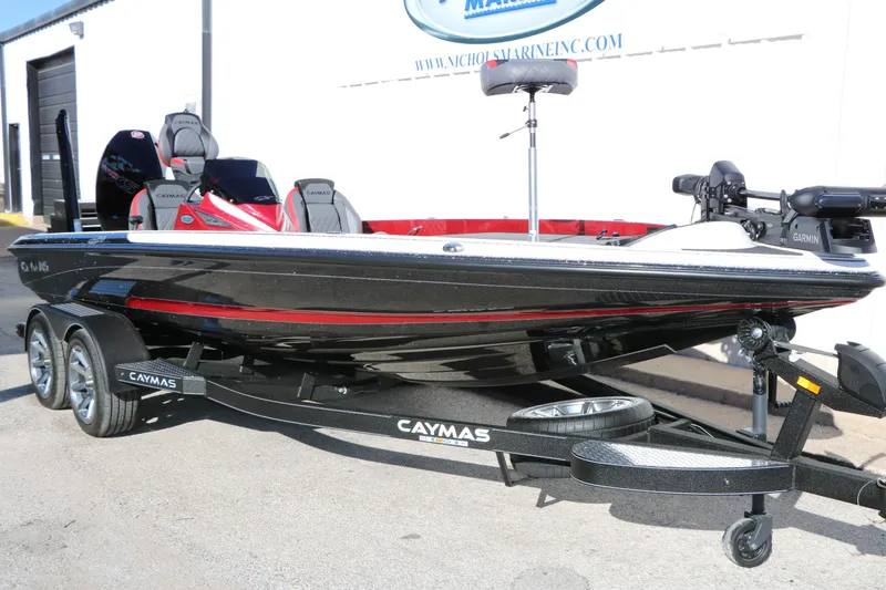 Slide: The Image of 2025 Caymas CX 20 PRO bass boat on trailer, black and red design, parked outdoors. - 3