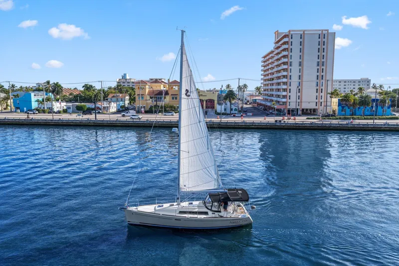 The Image of 2014 Beneteau Oceanis 37 sailboat cruising near urban waterfront buildings. - 1