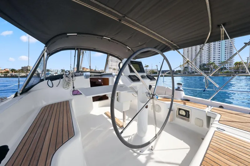 Slide: The Image of 2014 Beneteau Oceanis 37 sailboat cockpit with steering wheel, docked near waterfront buildings. - 17