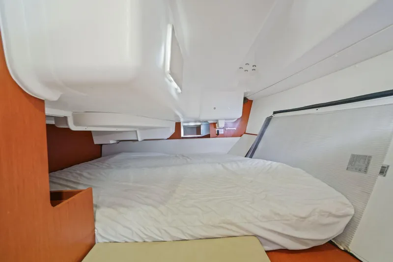 Slide: The Image of Interior cabin of 2014 Beneteau Oceanis 37 sailboat, featuring a cozy bed and wooden accents. - 26