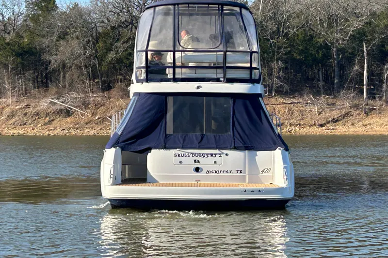 Slide: The Image of 2005 Sea Ray 44 Sedan Bridge yacht on a calm lake, rear view. - 2