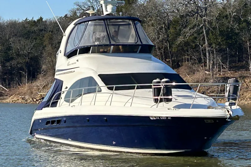 Slide: The Image of 2005 Sea Ray 44 Sedan Bridge yacht cruising on a calm lake with forested shoreline. - 3