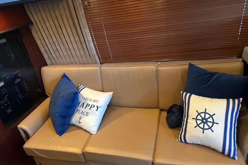 Slide: The Image of Interior of 2005 Sea Ray 44 Sedan Bridge with nautical-themed pillows on a beige sofa. - 39
