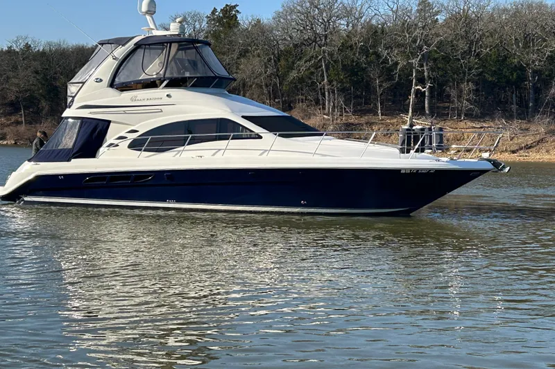 Slide: The Image of 2005 Sea Ray 44 Sedan Bridge yacht on calm water, surrounded by trees. - 48