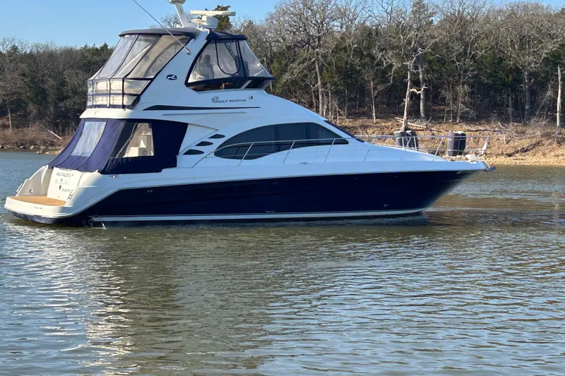 Slide: The Image of 2005 Sea Ray 44 Sedan Bridge yacht on calm water, surrounded by trees. - 5