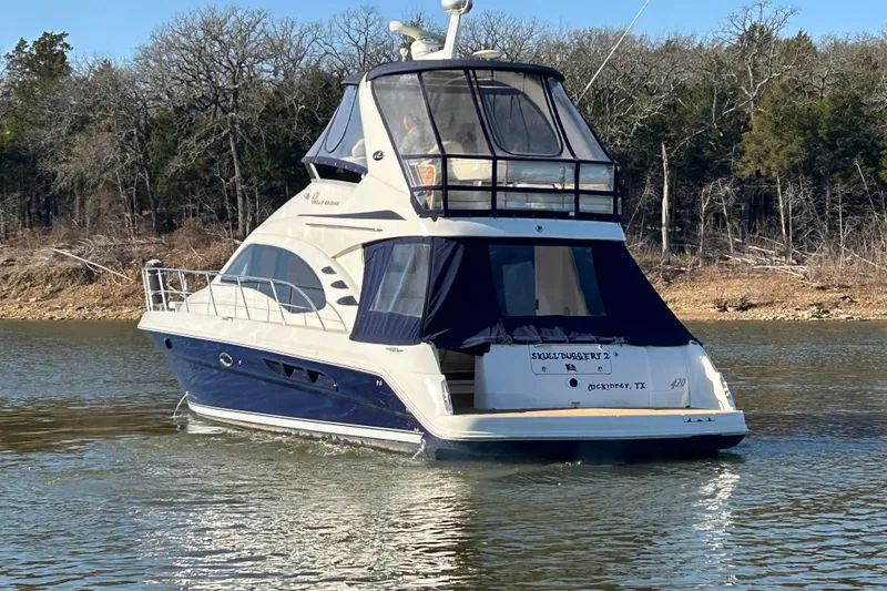 Slide: The Image of 2005 Sea Ray 44 Sedan Bridge yacht on a calm lake, surrounded by trees. - 51