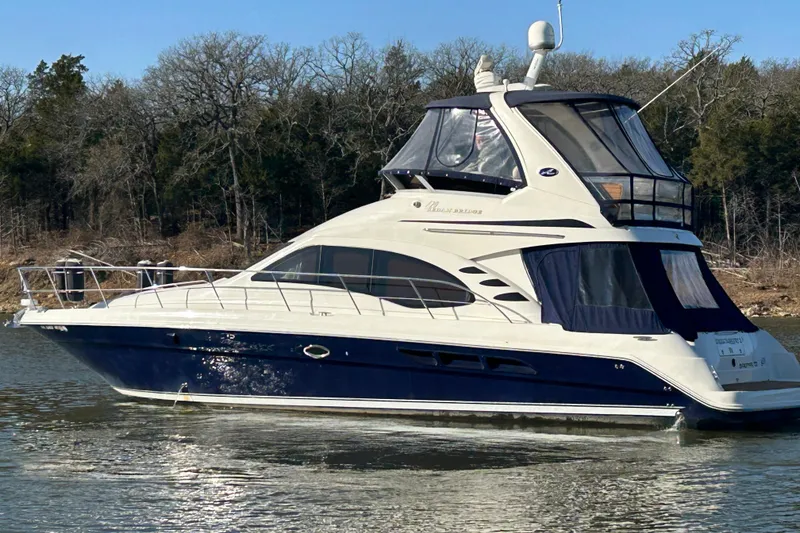 Slide: The Image of 2005 Sea Ray 44 Sedan Bridge yacht on calm water, surrounded by trees. - 53