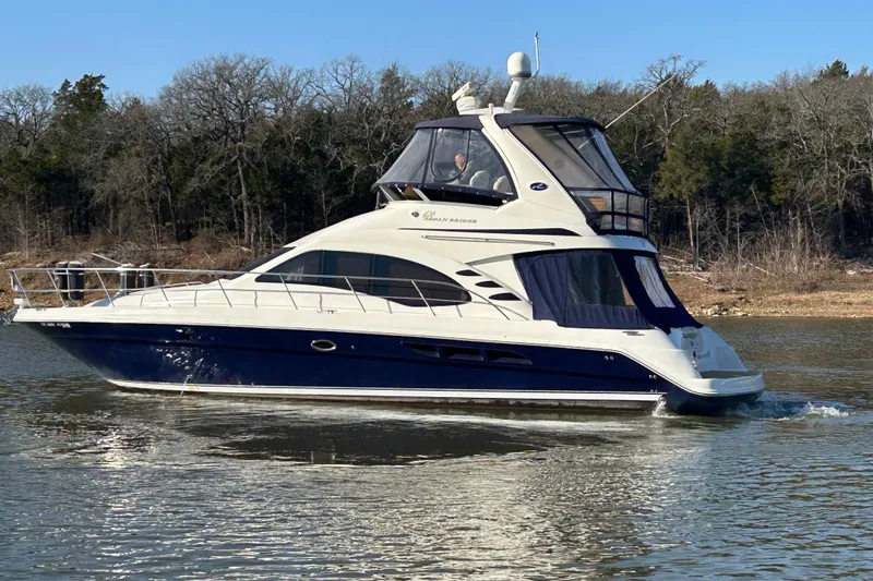 Slide: The Image of 2005 Sea Ray 44 Sedan Bridge yacht cruising on a calm lake with forested shoreline. - 54