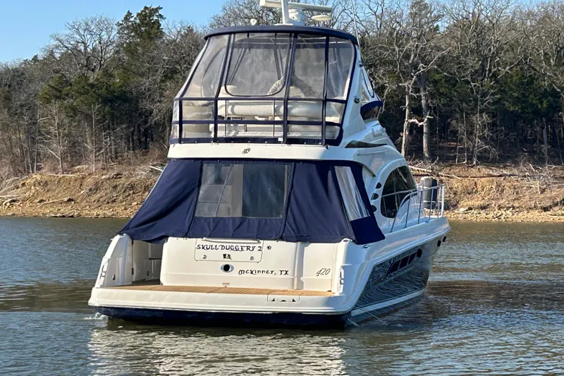 Slide: The Image of 2005 Sea Ray 44 Sedan Bridge yacht on a calm lake, surrounded by trees. - 6