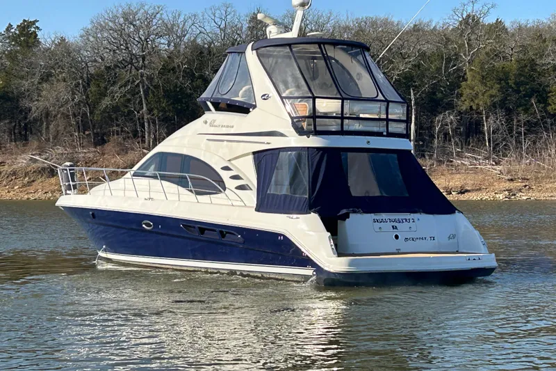 Slide: The Image of 2005 Sea Ray 44 Sedan Bridge yacht on calm water, surrounded by trees. - 7