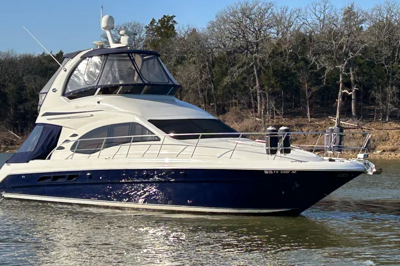 Slide: The Image of 2005 Sea Ray 44 Sedan Bridge yacht on calm water, surrounded by trees. - 8