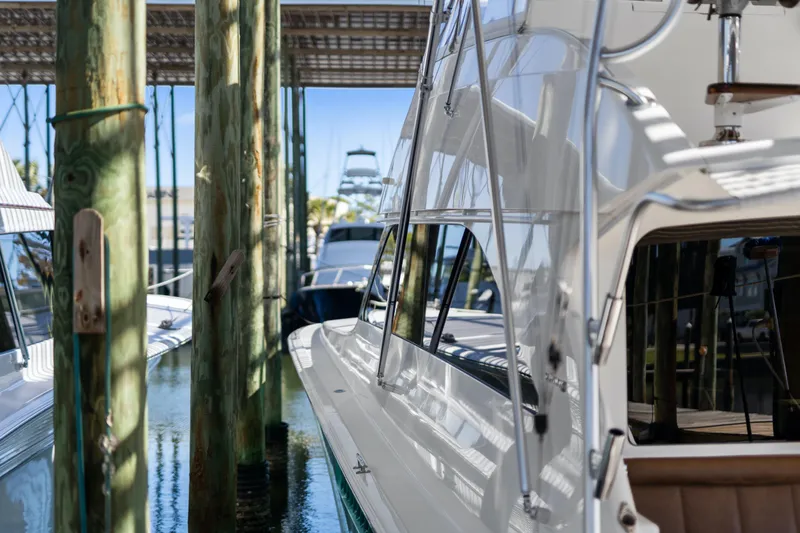 Slide: The Image of 2007 Viking 56 Convertible yacht docked in marina, surrounded by wooden pilings. - 59