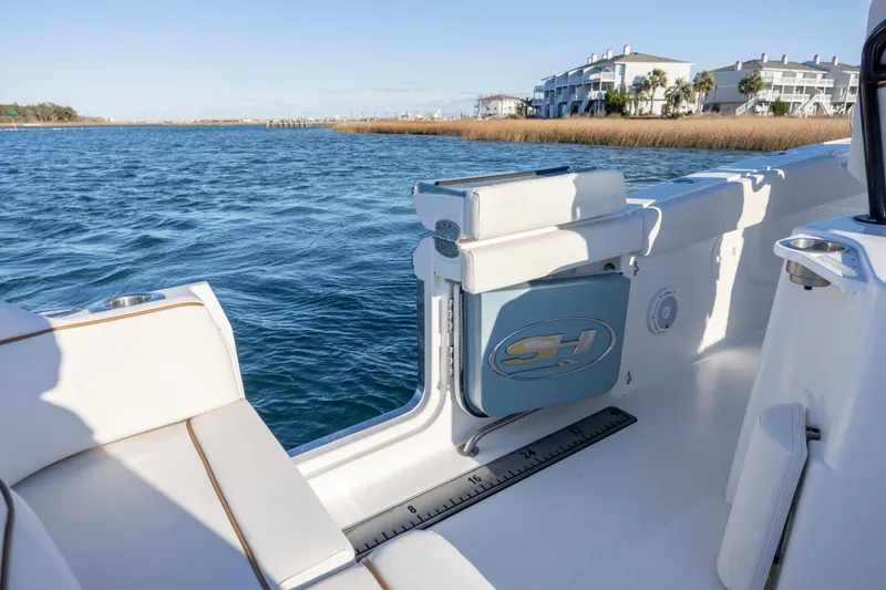 Slide: The Image of 2021 Sea Hunt Ultra 265 SE boat interior with seating, on calm water near shoreline. - 21