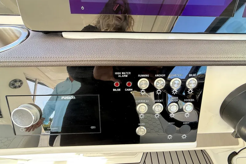 Slide: The Image of Control panel of 2022 Sea Ray Sundancer 320 Outboard with various switches and a Fusion audio system. - 27