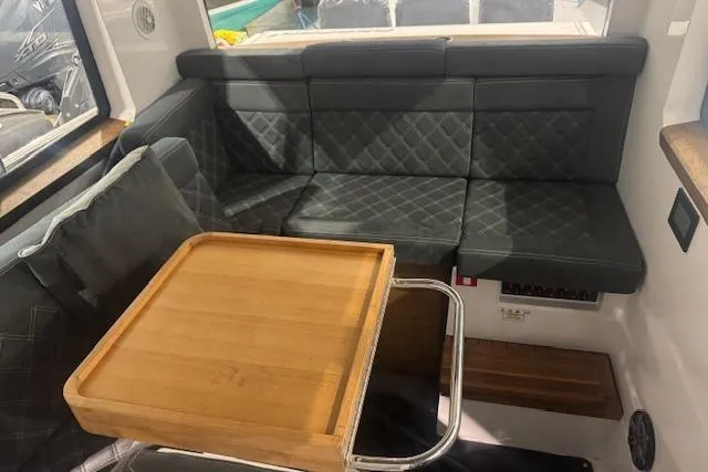 Slide: The Image of 2019 Axopar 37 XC Cross Cabin interior with black quilted seating and wooden table. - 11