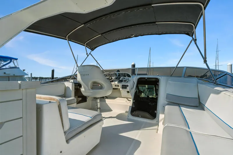 Slide: The Image of 2007 Meridian 490 Pilothouse interior with helm, seating, and canopy in marina setting. - 44