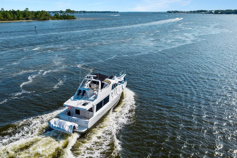 Slide: The Image of 2007 Meridian 490 Pilothouse yacht cruising on open water, scenic coastal backdrop. - 5