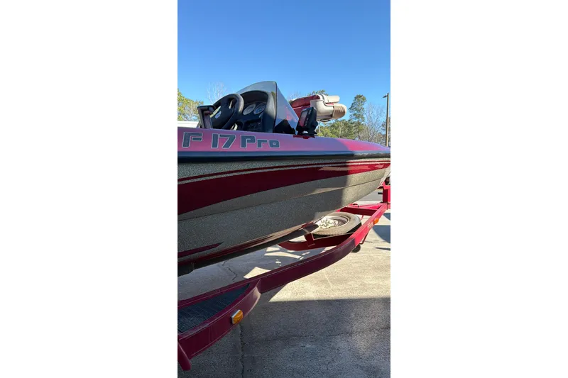 Slide: The Image of 1998 Fisher F 17 Pro boat on trailer, red and black design, clear sky background. - 6