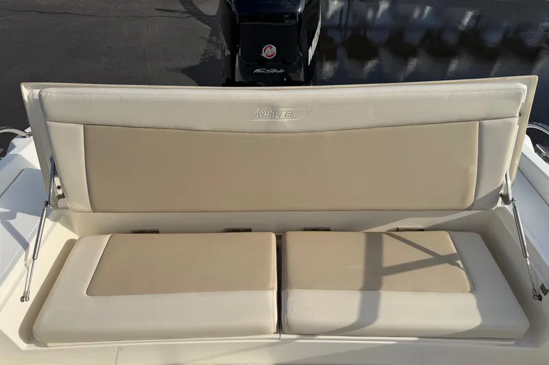 Slide: The Image of 2017 Boston Whaler 210 Dauntless boat seat with beige cushions and logo. - 15