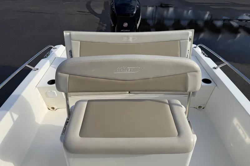 Slide: The Image of 2017 Boston Whaler 210 Dauntless boat seating area with beige cushions and stainless steel railings. - 16