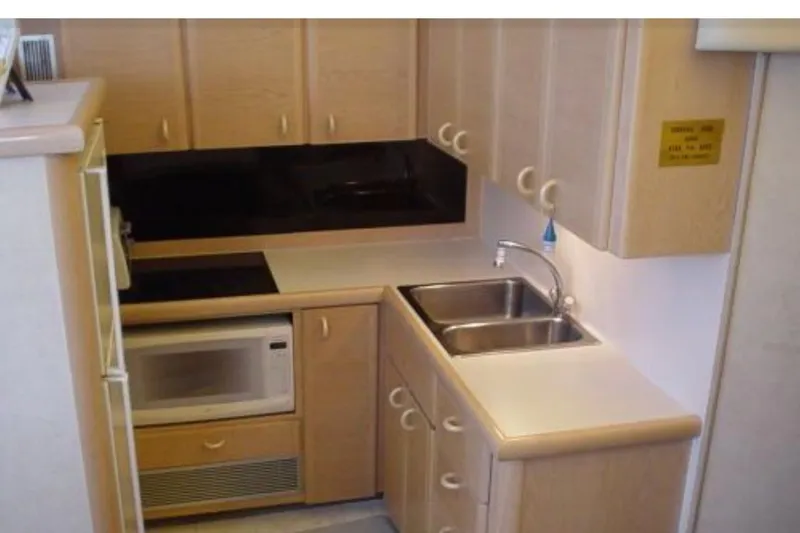 Slide: The Image of 1989 Silverton 46 Aft Cabin kitchen with sink, microwave, and wooden cabinets. - 5