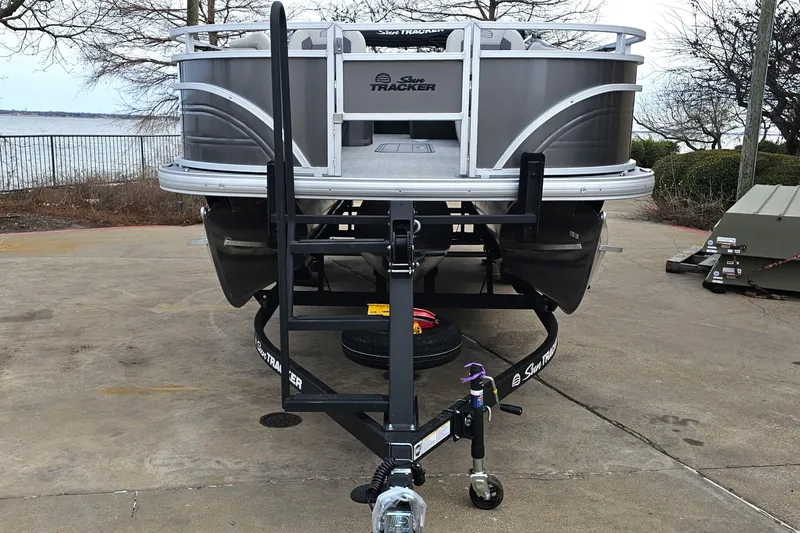Slide: The Image of 2026 Sun Tracker Fishin' Barge 22 XP3 pontoon boat on trailer, parked near a lake. - 4