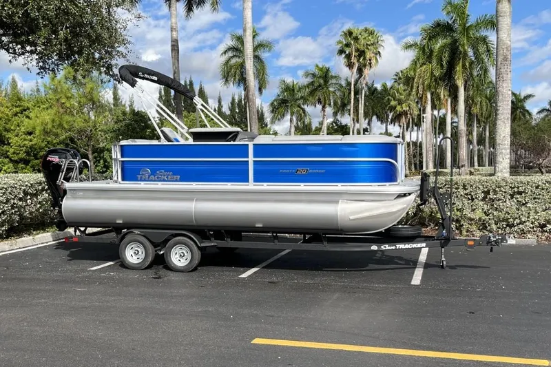 Slide: The Image of 2026 Sun Tracker Party Barge 20 DLX pontoon boat on trailer, parked in sunny lot. - 96