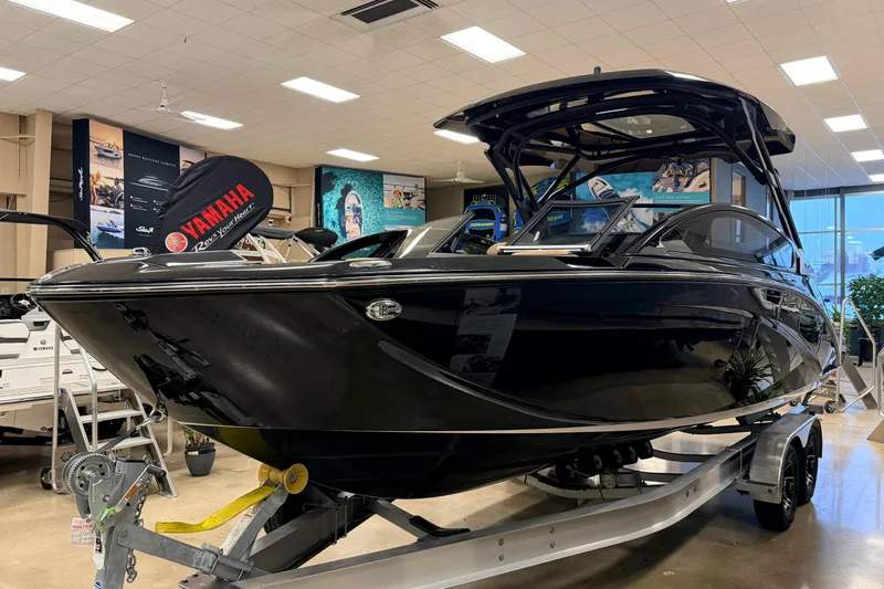Slide: The Image of 2026 Yamaha Boats 275SD in showroom, sleek black design on trailer. - 2