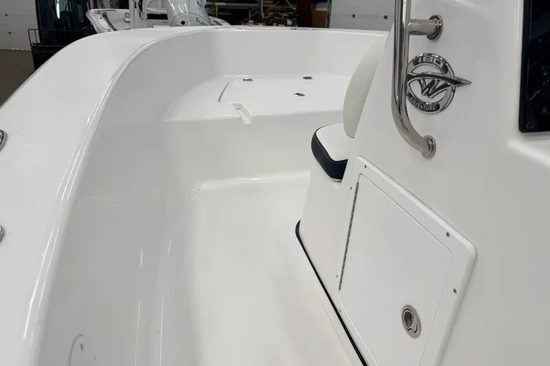 Slide: The Image of 2026 Tidewater 180 CC Adventure boat interior with seating and console in a warehouse. - 11