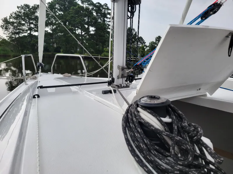 Slide: The Image of 2024 Zonda Z24 Base Model sailboat deck with rigging and open hatch, surrounded by trees. - 15