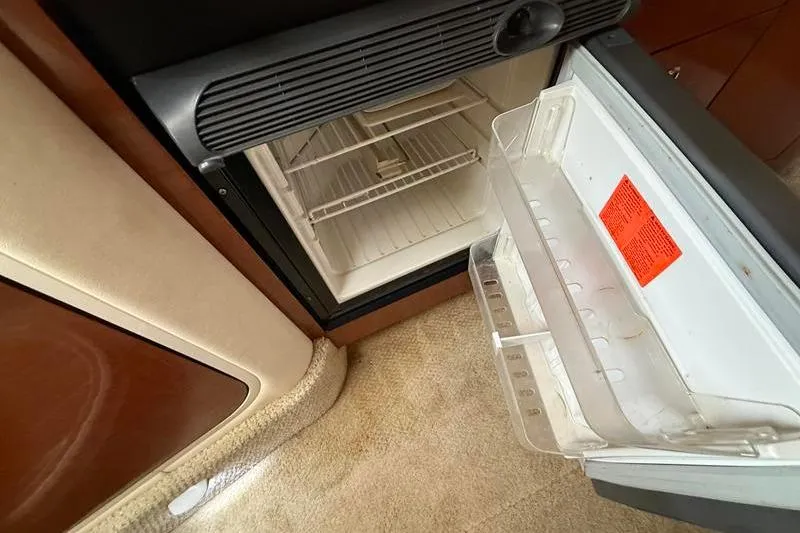 Slide: The Image of Open refrigerator inside 2003 Sea Ray 320 Sundancer yacht, showcasing interior storage space. - 20