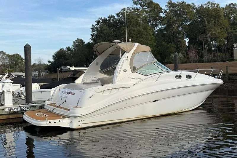Slide: The Image of 2003 Sea Ray 320 Sundancer boat docked on calm water, surrounded by trees. - 3