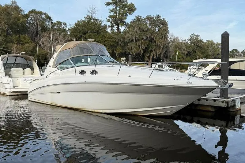 Slide: The Image of 2003 Sea Ray 320 Sundancer docked at a marina, surrounded by trees. - 4