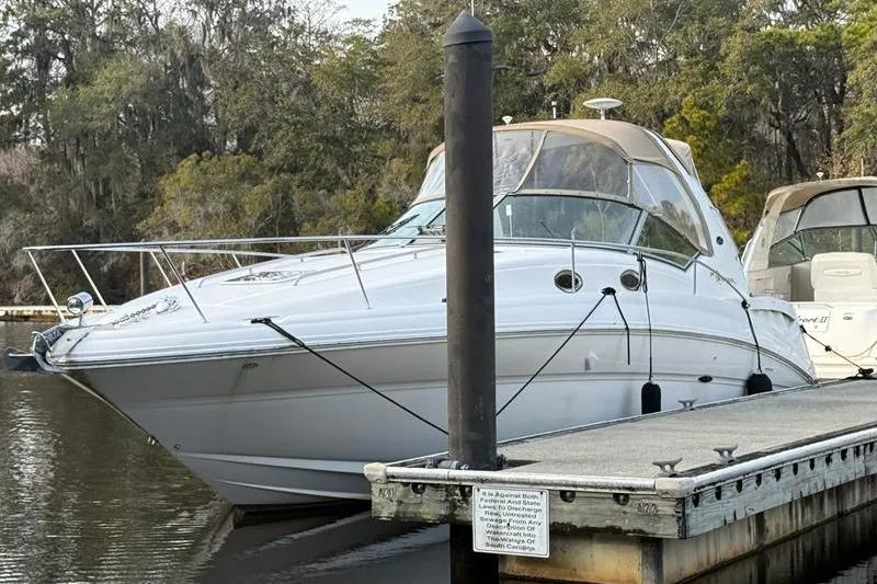 Slide: The Image of 2003 Sea Ray 320 Sundancer docked at a marina, surrounded by trees. - 5