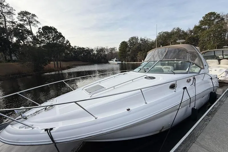 Slide: The Image of 2003 Sea Ray 320 Sundancer docked on a serene river with trees in the background. - 8