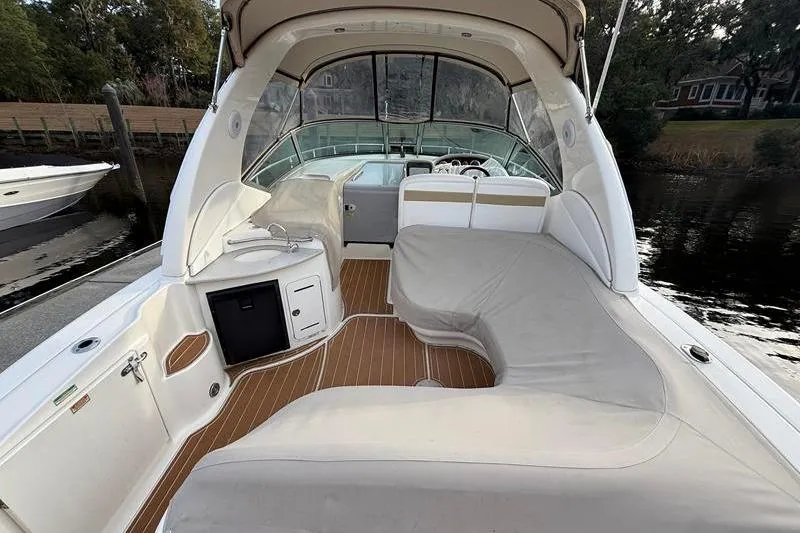 Slide: The Image of 2003 Sea Ray 320 Sundancer boat interior with seating and helm, docked by the water. - 9