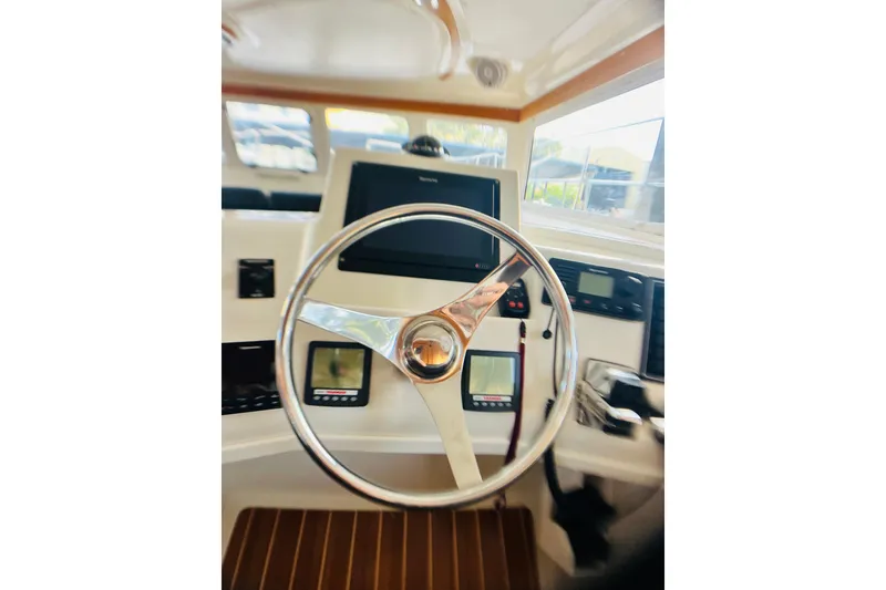 Slide: The Image of Steering wheel and dashboard of 2007 PDQ MV41 boat, featuring navigation controls. - 10