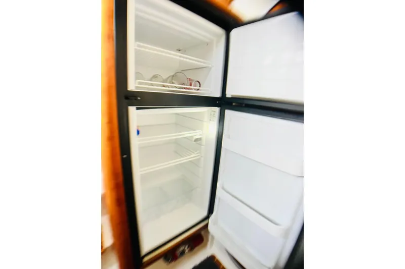 Slide: The Image of 2007 PDQ MV41 refrigerator with open doors, showing empty shelves and a few dishes. - 49