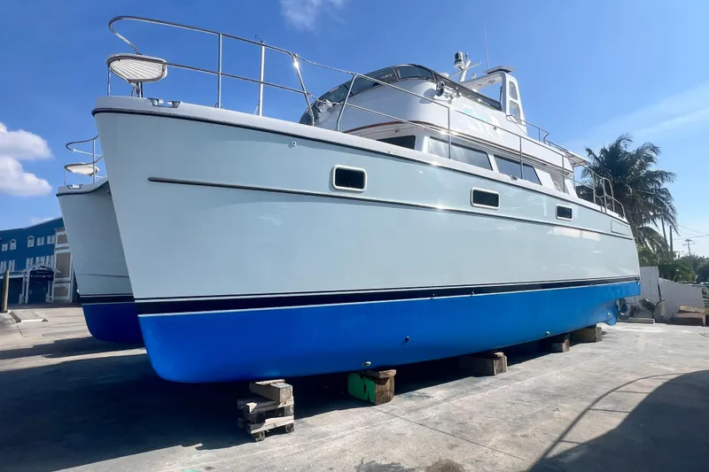 Slide: The Image of 2007 PDQ MV41 boat on dry dock, blue hull, clear sky background. - 74
