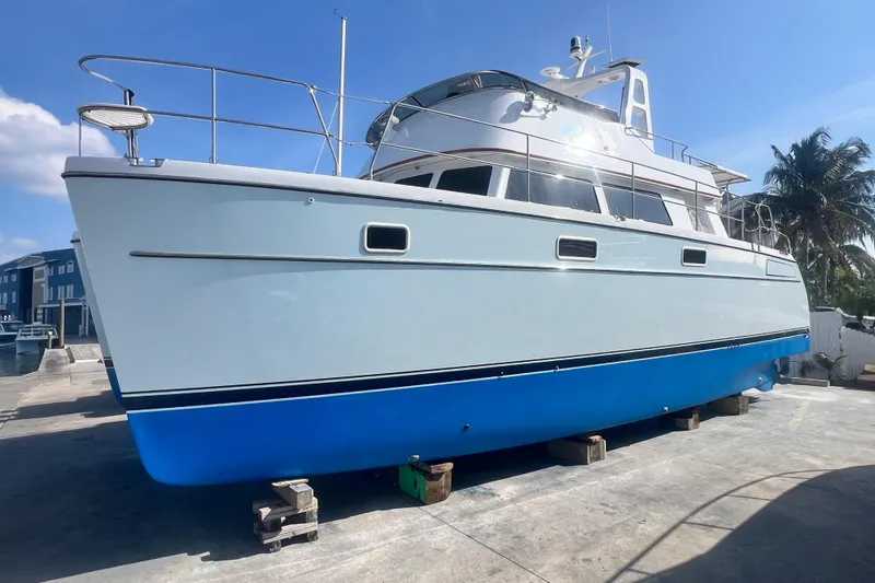 Slide: The Image of 2007 PDQ MV41 boat on dry dock, blue hull, sunny day, palm trees in background. - 75