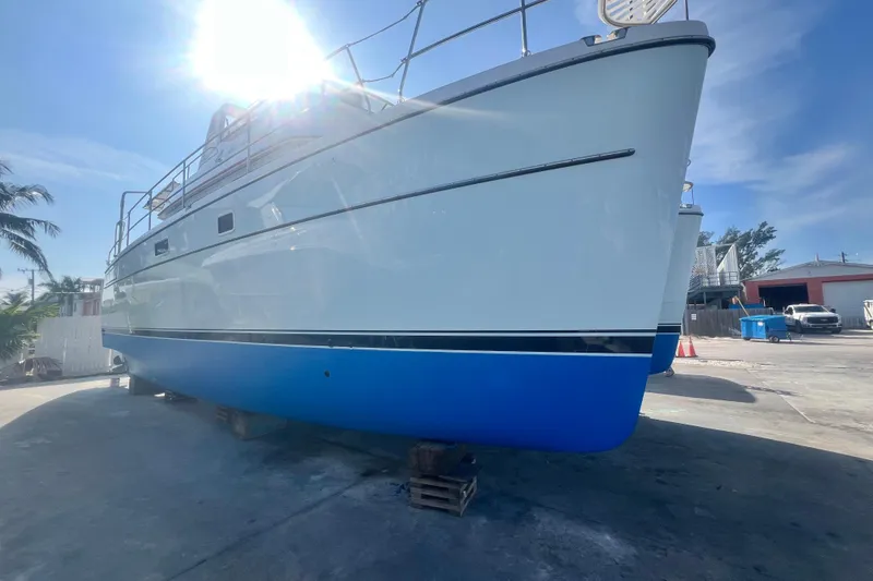 Slide: The Image of 2007 PDQ MV41 boat on dry dock, sunlit, with blue hull and white upper structure. - 76
