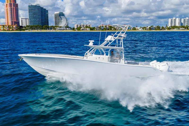 Slide: The Image of 2015 Yellowfin 42 Offshore boat cruising on blue ocean near city skyline. - 15