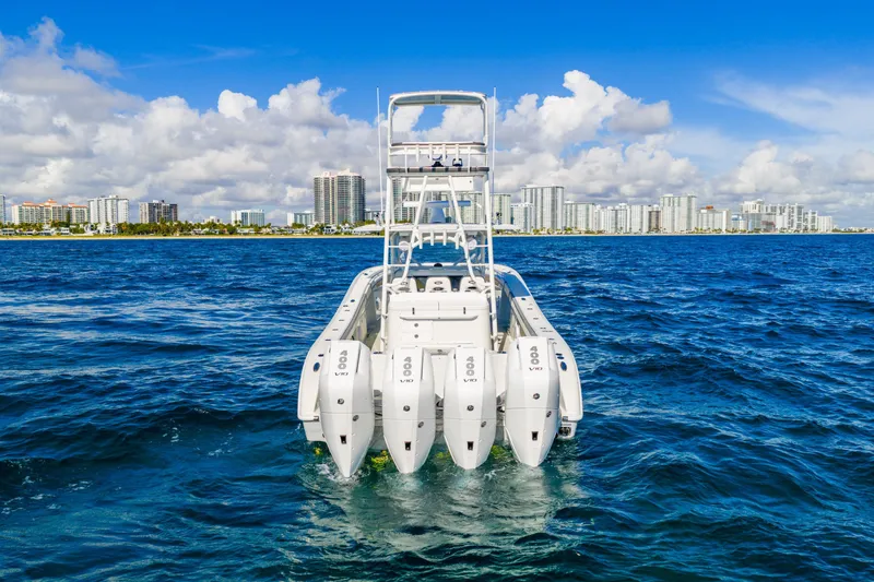 Slide: The Image of 2015 Yellowfin 42 Offshore boat with four engines on open water, city skyline background. - 18