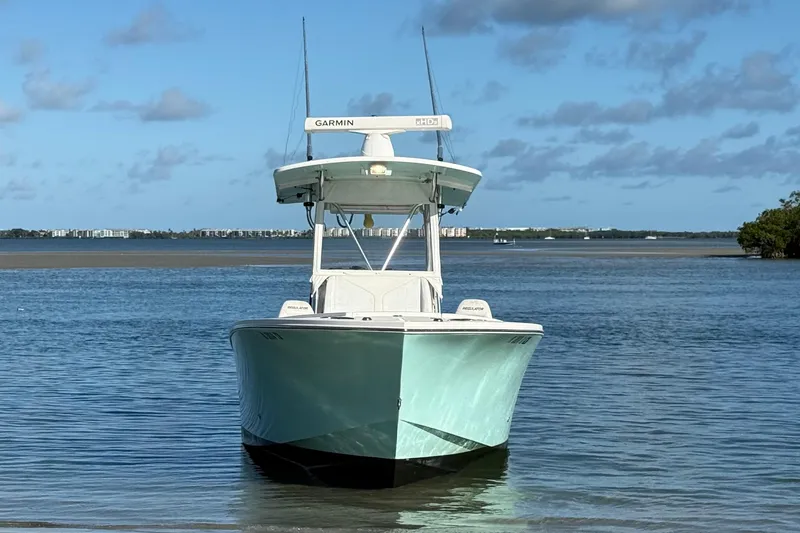 Slide: The Image of 2008 Regulator 26 Forward Seating boat on calm water under blue sky. - 2