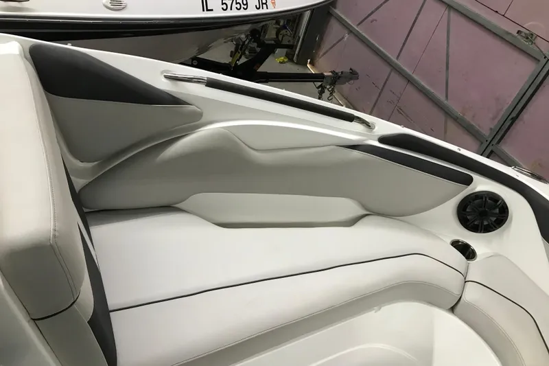 Slide: The Image of 2018 Rinker QX26 BR boat interior with white and gray seating, speaker, and cup holder. - 16