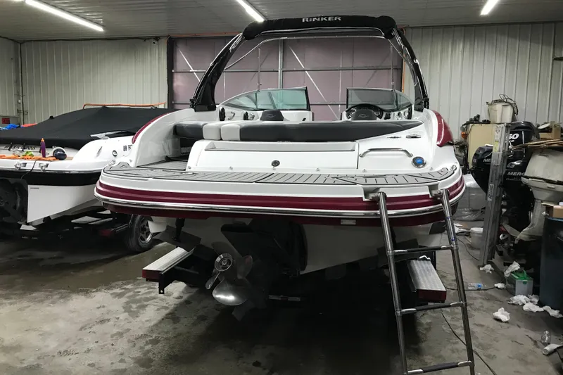 Slide: The Image of 2018 Rinker QX26 BR boat in a garage, rear view with ladder and propeller. - 28