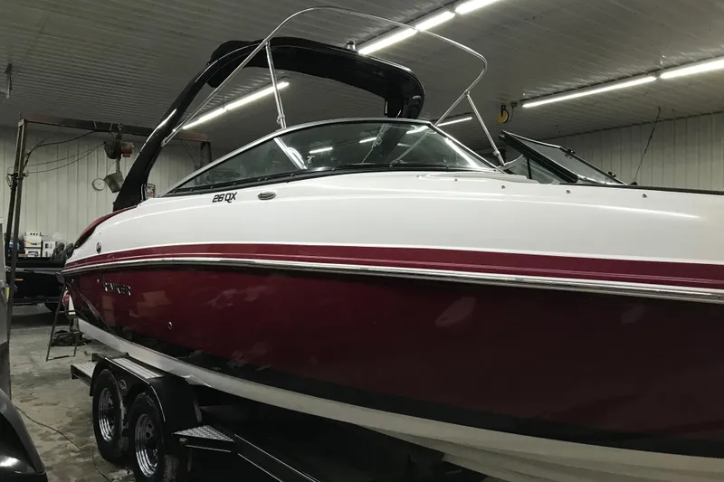 Slide: The Image of 2018 Rinker QX26 BR boat in a garage, featuring a sleek red and white design. - 29