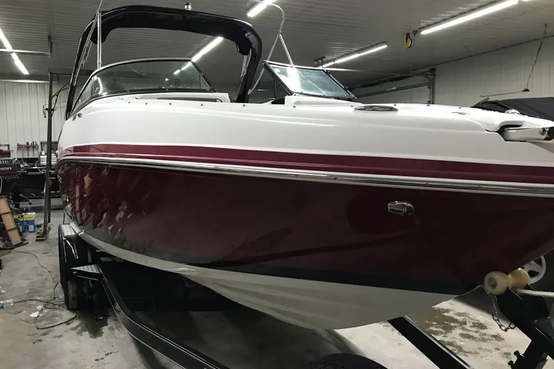 Slide: The Image of 2018 Rinker QX26 BR boat in a garage, featuring a sleek red and white design. - 30