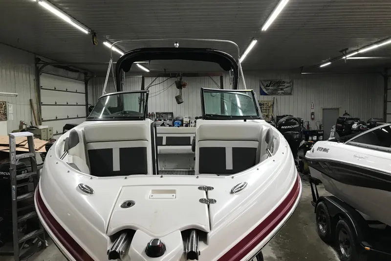 Slide: The Image of 2018 Rinker QX26 BR boat in a garage, showcasing sleek design and spacious seating. - 34